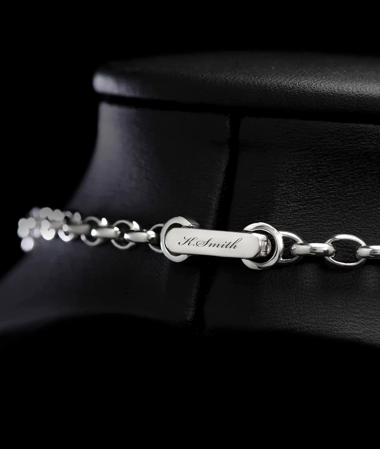 A clasp of a men's platinum rolo link chain necklace designed by ByEnzo Jewelry with engraving on the back of the chain
