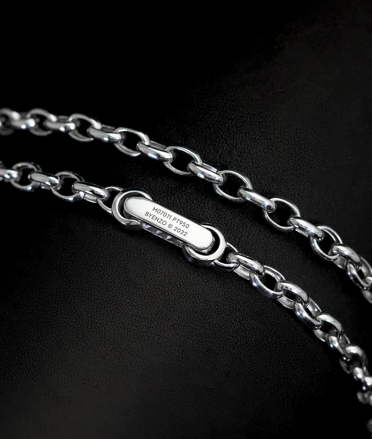 A clasp of a men's platinum rolo link chain necklace designed by ByEnzo Jewelry with engraving on the back of the chain