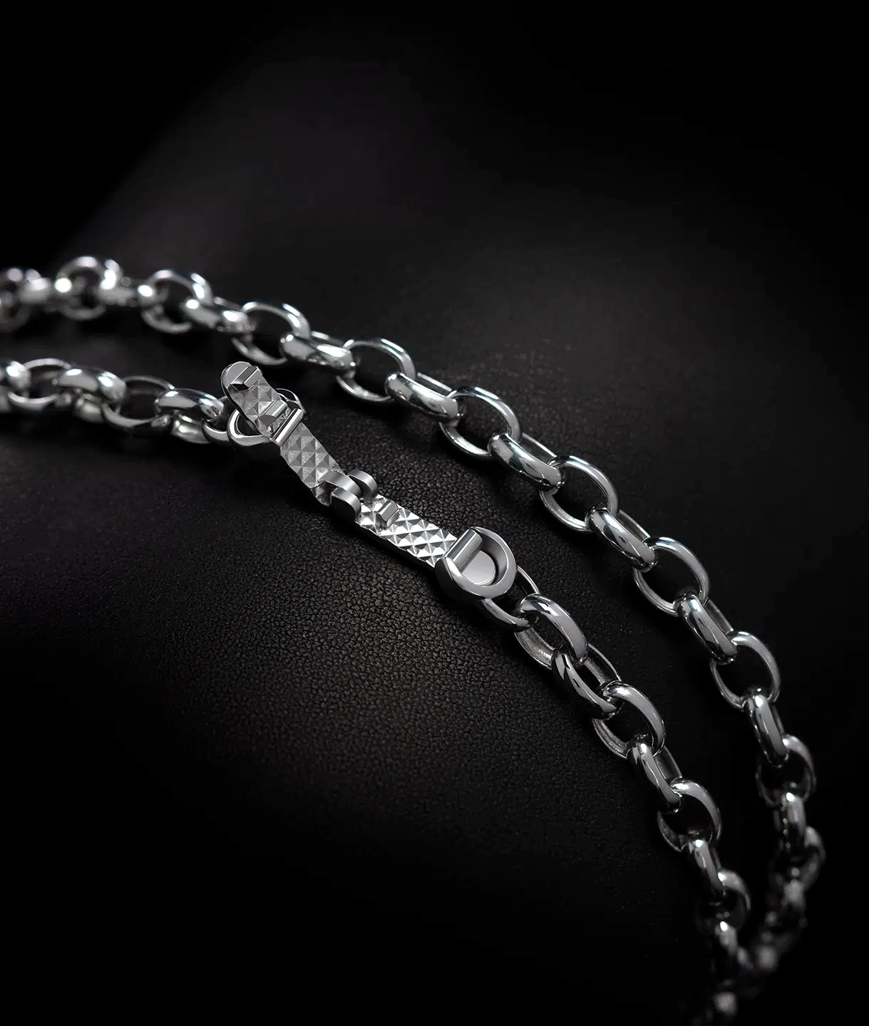 A clasp of a men's platinum rolo link chain necklace designed by ByEnzo Jewelry in a black background