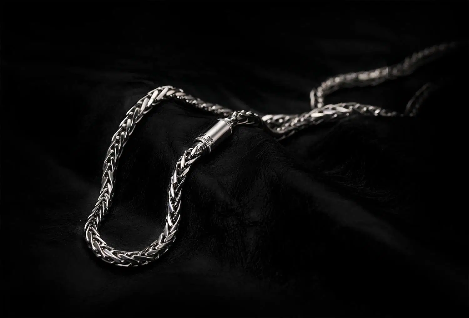 A clasp of a men's platinum wheat chain necklace designed by ByEnzo Jewelry with engraving on the chain