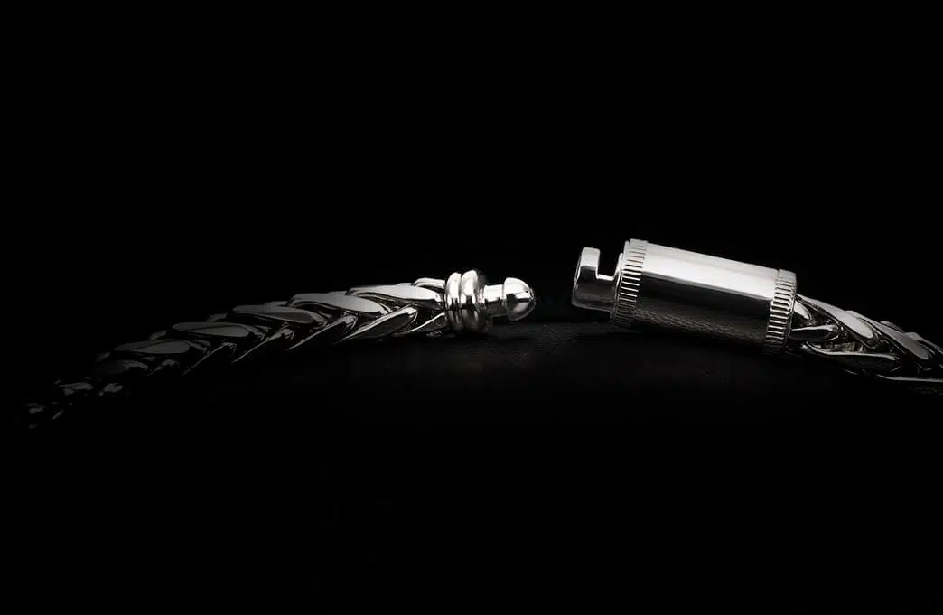 A clasp of a men's platinum wheat chain necklace designed by ByEnzo Jewelry in a black background