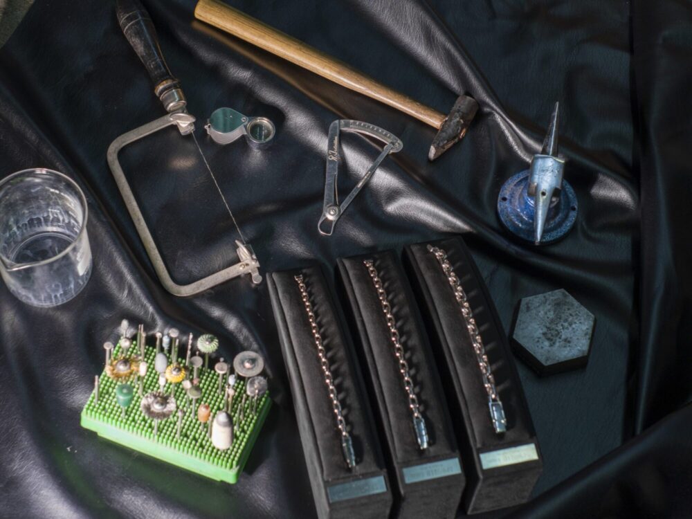I don't see a clear single jewelry product isolated in this image. The photo shows a collection of jewelry-making tools and supplies arranged on fabric, including various tools, a green bead organizer, and several black pouches with beaded items. If you'd like alt text for a specific jewelry piece from this collection, please provide a clearer close-up image of that individual item.